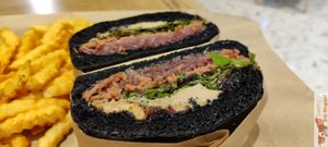 HAPPY DUCK "FOIE GRAS" BURGER : Baker's brioche bread with vegetable charcoal, Steak beyond smashed on a bed of onion confit, green young shoots, faux foie gras lined with 'fig jam at Vbb House in Paris