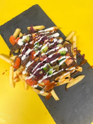 Loaded Fries: Crispy thin fries topped with our secretly made doner meat, tomato, cucumber, pickled red cabbage, in-house garlic and chilli sauce  at Dirty Vurgerz in London