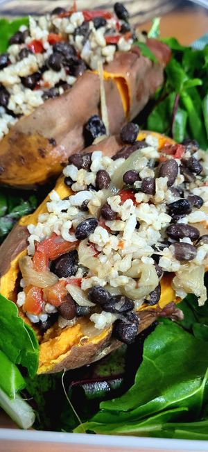 Batatas rellenas con frijoles negros salteados con vegetales y especias + arroz integral con fondo de hojas verdes del huerto #Veganuary at Alimentum in Malaga