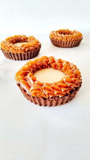 Base de galletitas tipo chocolinas, ganache de chocolate semiamargo, ganache de chocolate blanco y dulce de leche. Tiene azúcar refinada. at Nati's Pasteleria Artesanal  in Buenos Aires