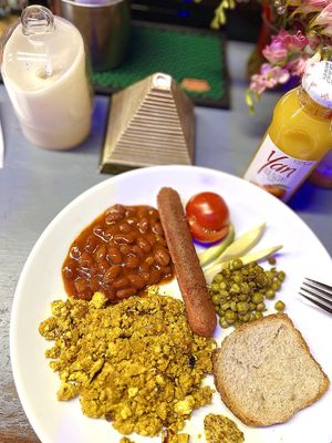 English vegan breakfast: fried vegan sausage, scrambled tofu with onions, red beans in tomato chili sauce, fried green peas, fresh tomatoes, mustard and orange juice at TUF Club in Yerevan