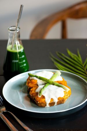Tofu benedict toast on gluten-free pumpkin bread. Served with pure green juice. at Living Food Lab Canggu in Canggu
