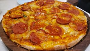Pepperoni pizza (950 rupees). Excellent pepperoni. Cheese tastes good but is too liquid. Crust was overdone. at Earth Cafe @ Juhu in Mumbai