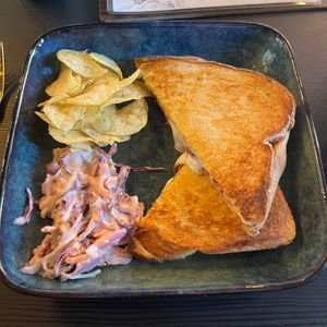 plate with crisps, vegan slaw, and a vegan brie and cranberry toastie at Oscar's Cafe in St Neots
