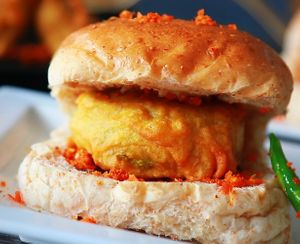 Masala Vada Pav is a popular street food from Mumbai, India, consisting of a spiced lentil fritter (vada) sandwiched between a bread roll (pav) and served with chutney and fried green chili. at Jagdish Farshan in Irving