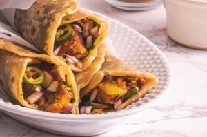 Frankies are a popular Indian street food consisting of a wrap filled with spicy and savory fillings, such as Aloo tikki or paneer,  vegetables, and garnished with chutney and onions. at Jagdish Farshan in Irving
