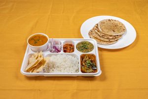 Gujarati Thali is a traditional Gujarati meal that features an assortment of vegetarian dishes including dal, kadhi, vegetables, roti, rice, pickles, chutneys. at Jagdish Farshan in Irving
