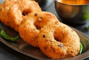 Medu Vada is a popular South Indian breakfast or snack food made with a batter of urad dal, deep-fried until crispy on the outside, and served with chutney and sambar. at Jagdish Farshan in Irving