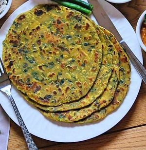 Thepla is a popular Gujarati flatbread made from a dough of whole wheat flour, fenugreek leaves, and spices, rolled out thinly and cooked on a griddle with oil until golden brown. at Jagdish Farshan in Irving