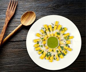 Khandvi is a popular Gujarati snack made by cooking a spiced batter of gram flour and yogurt, spreading it thin, rolling it up, and garnishing it with tempered spices and grated coconut. at Jagdish Farshan in Irving