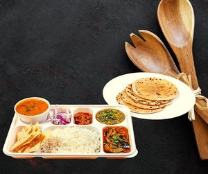 Gujarati Thali is a traditional Gujarati meal that features an assortment of vegetarian dishes including dal, kadhi, vegetables, roti, rice, pickles, chutneys. at Jagdish Farshan in Irving