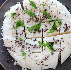 Dhokla is a steamed savory snack from Gujarat, India, made with a fermented batter of gram flour and often served with a tempering of mustard seeds and curry leaves. at Jagdish Farshan in Irving