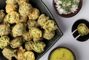 Methi Gota is a popular Gujarati tea-time snack made with chickpea flour, fenugreek leaves, and spices, deep-fried until crispy and served with chutney(Gota). at Jagdish Farshan in Irving