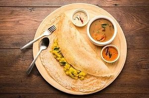 Masala Dosa is a South Indian dish made with a crispy crepe-like batter of rice and lentils, filled with a spiced potato and onion filling, and served with chutney and sambar at Jagdish Farshan in Irving