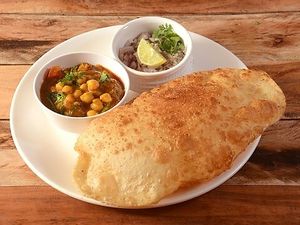 Chole batura is a popular North Indian dish consisting of spicy chickpea curry (chole) and deep-fried puffy bread (batura), often served with pickles and onion salad. at Jagdish Farshan in Irving