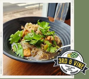 A rich broth of galangal, panda, black soy, garlic, chilies, and sesame. Served with mushrooms, onion, celery, lemon grass, tofu, and rice noodles.  Topped with pickled brussel spr at 3rd & Vine in Eau Claire