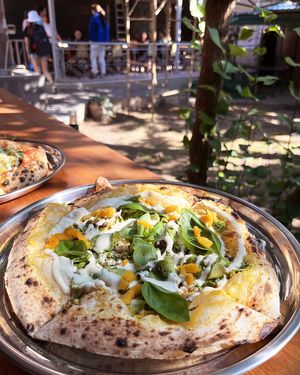 Vegan pizza with apricot mash, baked tofu, pesto, slices of squash, kalamata olives and marinated apricots at 2022_bak in Yerevan
