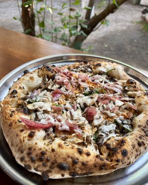 Vegan pizza with mushrooms, smoked tofu, marinated onions, "cream" sauce and greens at 2022_bak in Yerevan