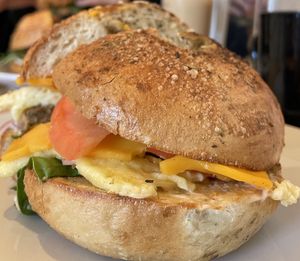 Vegan egg, vegan cheddar, vegan sausage, vegan spicy mayo, tomato, red onion, and spinach on a garlic and herb bagel  at Wee Bird Bagel Cafe in Randolph
