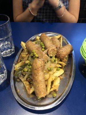 Salchichas al vino. 100% recomendable. Un plato con salchichas sazonadas con especias y vino adobadas con guisantes y cebolla sobre una capa de patatas fritas.   at B13 Bar in Madrid