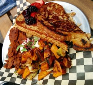 Champions of breakfast plate: French toast, savory tofu scramble, organic berries, maple glazed seitan bacon, broccoli rabe/Brussels sprouts/sweet potato hash.  at Hella Vegan Eats in Oakland