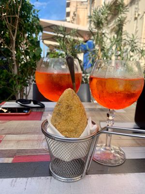 Anne enjoying an Aperol spritz, arancini pairing at Vegan Food Tour Ortigia in Siracusa