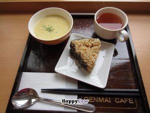 A brown rice triangle with crushed sesame seeds on the side, some soup, and some tea. at Genmai Cafe in Osaka
