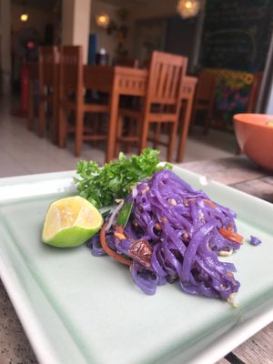 Scoop from the big plate of butterfly pea pad Thai. at Anchan Vegetarian Restaurant in Chiang Mai