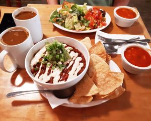 Chiliguacamole (bean chili, guacamole, vegan sour cream, and brown rice, served with tortilla chips), Breakfast Plate (tofu scramble, pico de gallo, tempeh bacon, toast, and salad), Americanos with homemade almond coconut milk, and complimentary gazpacho. Photo taken June 2018. at Resonance Cafe in Montreal