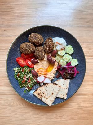 Gray pea and chickpea falafel bowl with sun-dried tomato hummus, tabbouleh, fermented beetroot and tzaziki sauce. at Booch Cafe in Riga