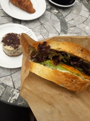 Sandwich with carrot, avocado, vegan cream cheese, lettuce and stracciatella cake in the back at MiiT in Riga