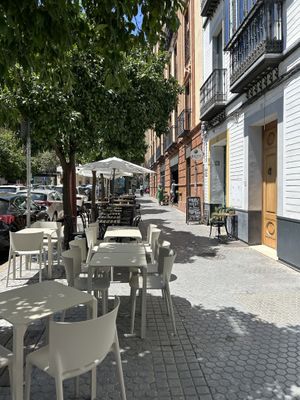 Outside the shop front: some outdoor seating with parasols for shade  at Balino Yoga Café  in Sevilla