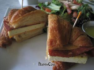Croissant breakfast sandwich with veggie bacon and tofu and a sauce.  Plus, a side salad. at LA Vegan Crepe in Los Angeles