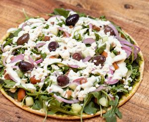 Athena FLAT: Spinach, white bean and herb spread layered on thin lavash bread and topped with arugula, tomatoes, cucumbers, kalamata olives, pickled red onion, and crumbled feta. at worldFLATS - Montclair in Montclair