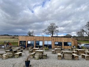 Exterior of building and outside tables + small play area   at Highland Farm Cafe in Dingwall