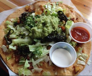 Peppers at the Gates of Dawn special: spicy seitan sausage, lettuce, guac, fried poblano peppers, papas, salsa & sour cream atop a fried tortilla! at Green New American Vegetarian in Tempe