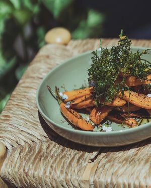 Zero-waste km0 carrots with orange reduction, almonds, plant based feta, and crispy leaves at botànic in Barcelona