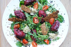 Salad with spinach, rocket, herbal-almonds cottage 'cheese', sunflower-tomato crisps, tomatoes and black olives powder with beetroof gnocci and sweet balsamic sauce. at Vega in Wroclaw