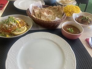 Vegetable biriyani, accompanying sauce, tandoori roti and Kathmandu aloo. Pilau rice in the background   at Buddha's Eye Indian Restaurant in Mallorca