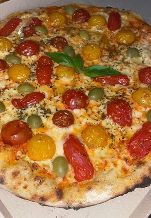 Vegan pizza with aquafaba garlic sauce, cherry tomatoes, green olives, basil leaves, oregano, olive oil at Crust in Yerevan