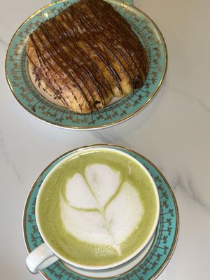 Matcha tea latte - this is the small cup - alongside the chocolate croissant    at Unicorniverse Bakery & Cafe in Round Rock