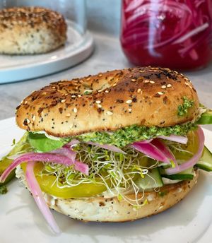 The Green Goddess - toasted everything bagel, creamy pesto spread, avocado. cucumber, sprouts, green tomato and pickled onion. at Vibrant Beat Cafe in Fort Myers