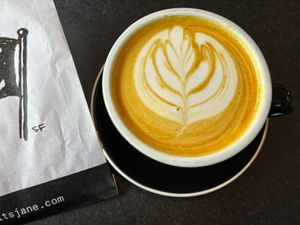 Golden turmeric latte with almond milk (snickerdoodle cookie in neighboring bag) at Jane on Larkin in San Francisco