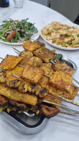 a selection of skewers, visible are tofu, vegan chicken, garlic, mushroom and rice cake. at the back are diamond shaped fried noodles and a side salad at Halimai Roasted Mutton - 哈利麦烤羊肉店 in Zhangye
