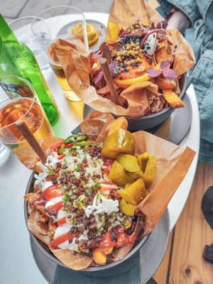 [May 2023] Dutch special (vegan). Spicy ketchup, mayo, onion mix, jewish pickles, nutmeg crumble.
In the backgroud: Mideast (vegetarian). at Pom Friterie in Stockholm