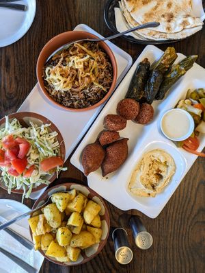 Mujadara; vegan platter (vine leaves, cabbage rolls, kibbeh, falafel, hummus); potatoes with kizbara. at Shamiat Authentic Syrian Restaurant in Northcote