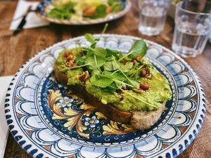 Vegan avo sourdough toast with a generous topping of avocado, chili nut oil, dukkah, and watercress. at Society Bar & Kitchen in Edinburgh
