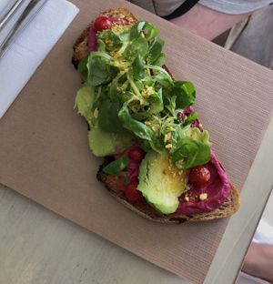 Tostada con hummus de remolacha y hierba buena, aguacate, tomates cherry, canónigos y rawmesan 🥑🍅  at La Aldea Cafe Bar in Conil De La Frontera