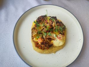 Roasted cauliflower on a bed of hummus and toasted chickpeas with a sauce of pomegranate and sweet curry, decorated with pea-greens. at Ponte Porton in Groznjan