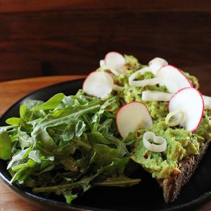 Seeded rye toasted with smoked gouda and topped with smashed avocado, leek powder, radish, pickled leeks, Aleppo pepper, and black sesame. (Vegan if you ask for no cheese!)   at Sparrow Coffee in Naperville